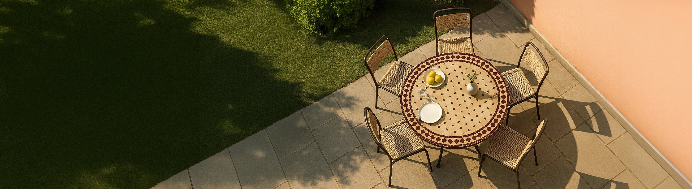 Mosaikborde Ø100 – Stort rundt mosaikbord Ø100 cm med zellige fliser og flere stole på terrassen i haven fra fugleperspektiv med varm sol