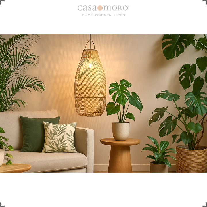 Stor rattan loftslampe over sofa i stue med masser af grønne planter og varmt lys