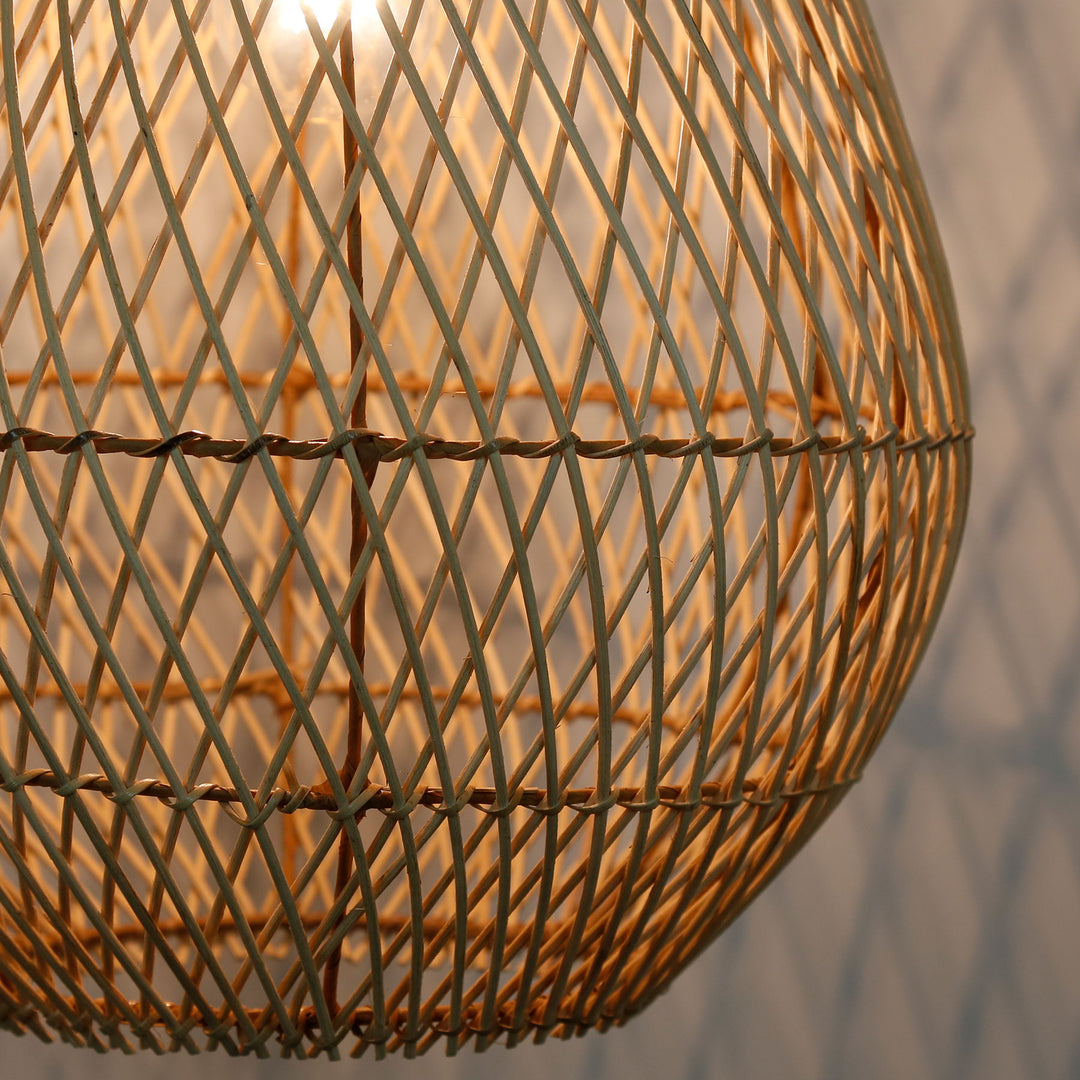 Detaljeret billede af en håndlavet rattanlampe med et fint, diagonalt vævningsmønster og varmt lys